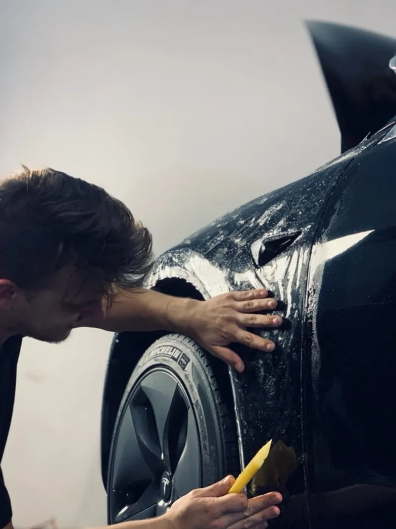 PPF installation - installer applying 3M paint protection film to vehicle fender